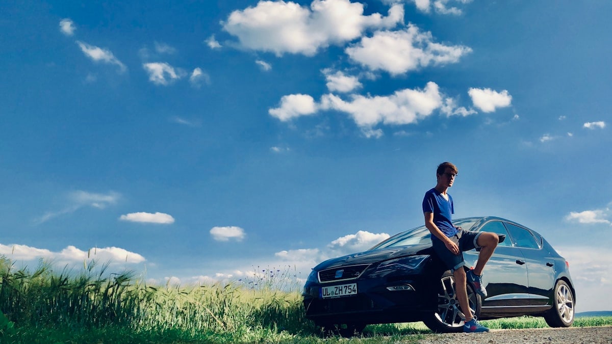 man leaning beside black sedan